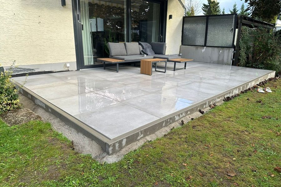 Neue Terrasse mit großformatigen hellen Platten und Lounge-Möbeln