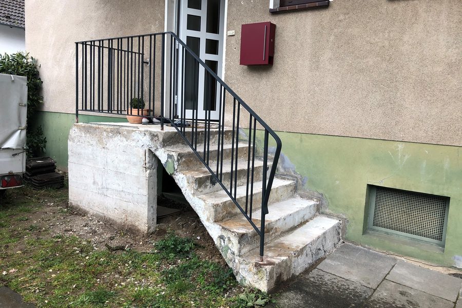 Derselbe Hauseingang vorher: verwitterte Betontreppe mit altem Geländer