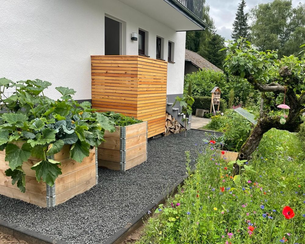 Angelegter Vorgarten mit Hochbeeten, Holz-Sichtschutz, Kiesweg und Blumenwiese